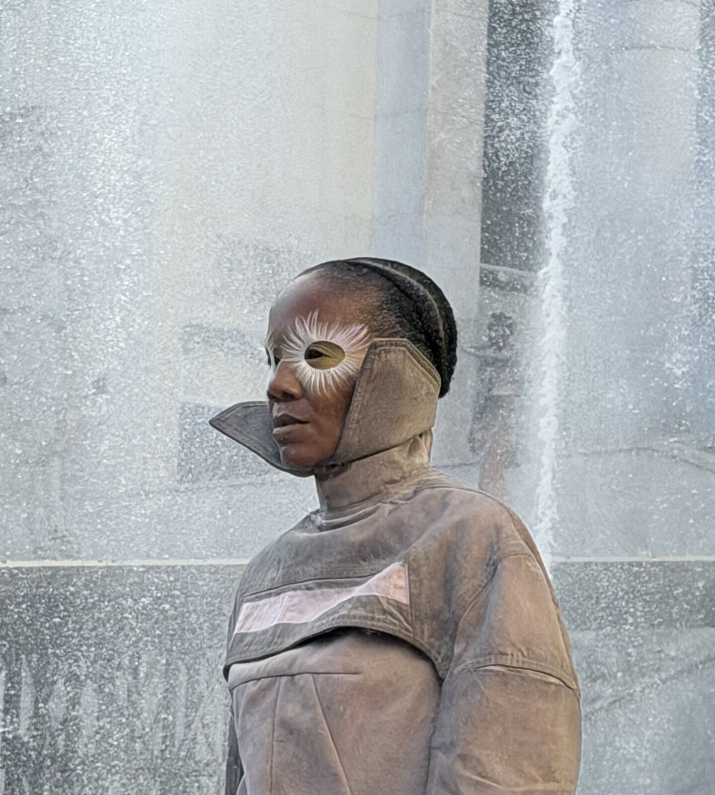 Close view of a model in taupe sculptural face styling with metallic eye detail